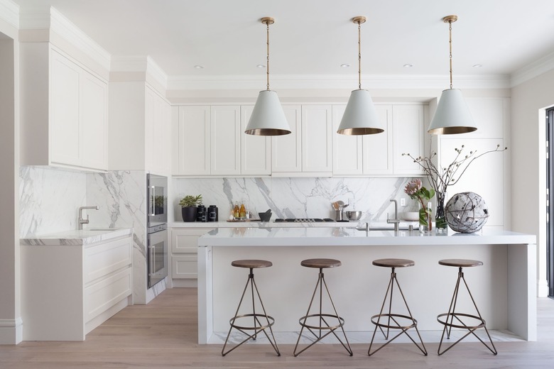 modern white kitchen with sculptural bar stools and conical pendant lights