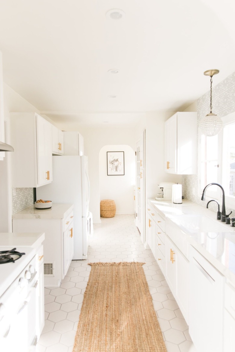 all white kitchen with sisal runner rug and gold hardware on cabinets