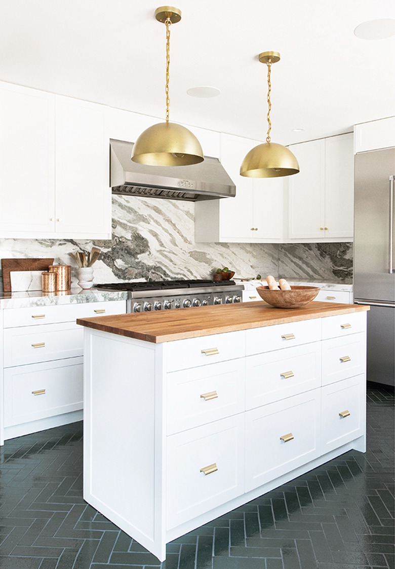 white modern kitchen with marble backsplash and brass dome pendants