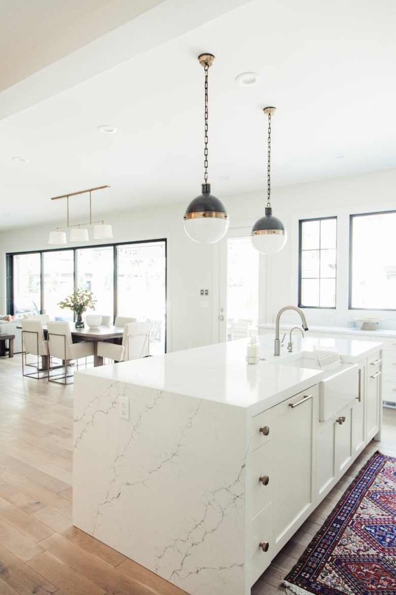 open concept white kitchen with vintage rug and modern pendant lights