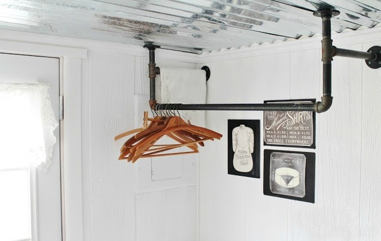 Black cast-iron piping hangs from the ceiling of a white laundry room.