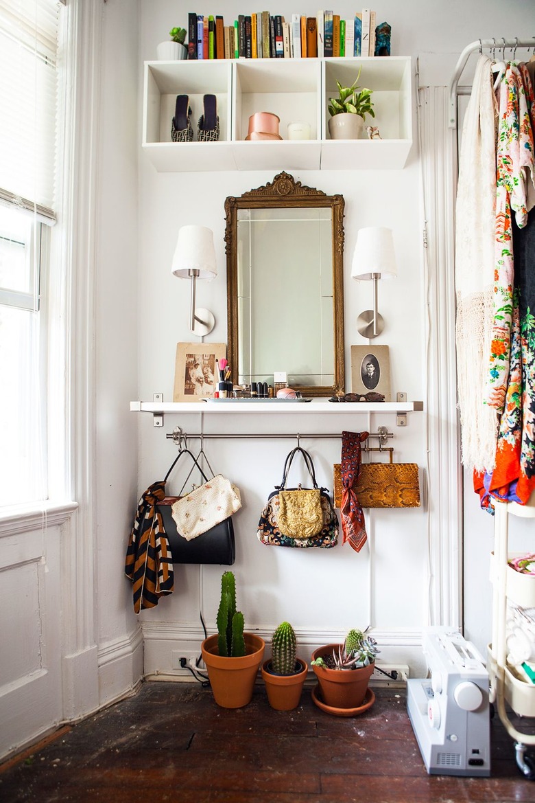 Purses hanging from a closet rod beneath a white shelf