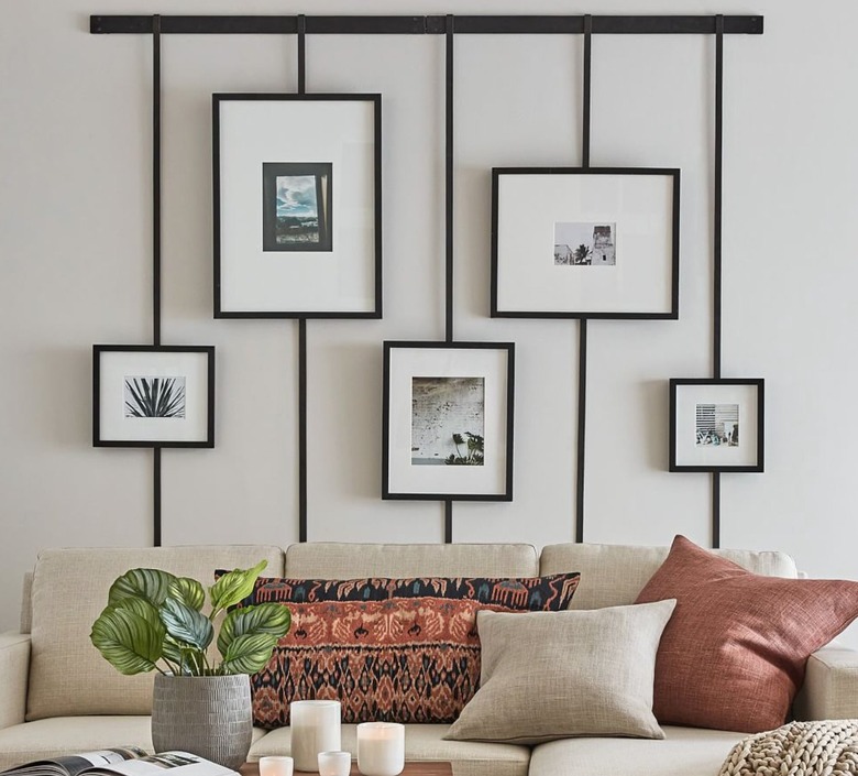 Couch, pillows, plant, picture frames hung on rack.