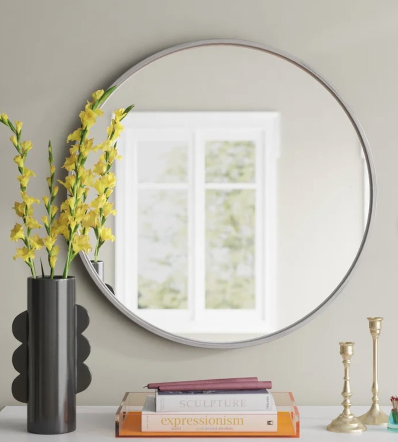 Round mirror, vase, flowers, books, candle sticks.