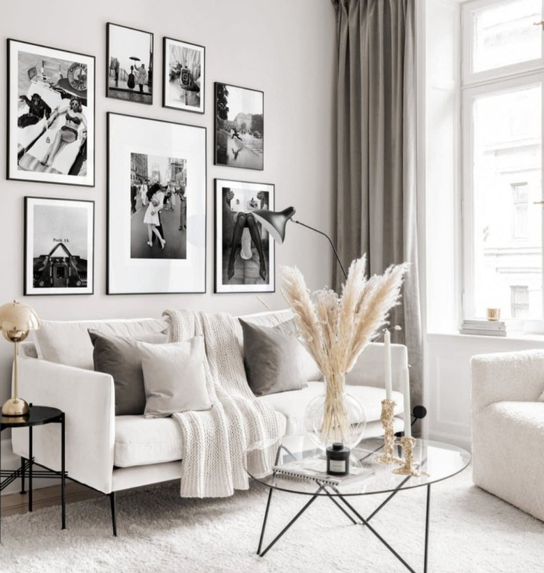 Living room with couch, pillows, coffee table, dried grass, lamp, black and white gallery wall.