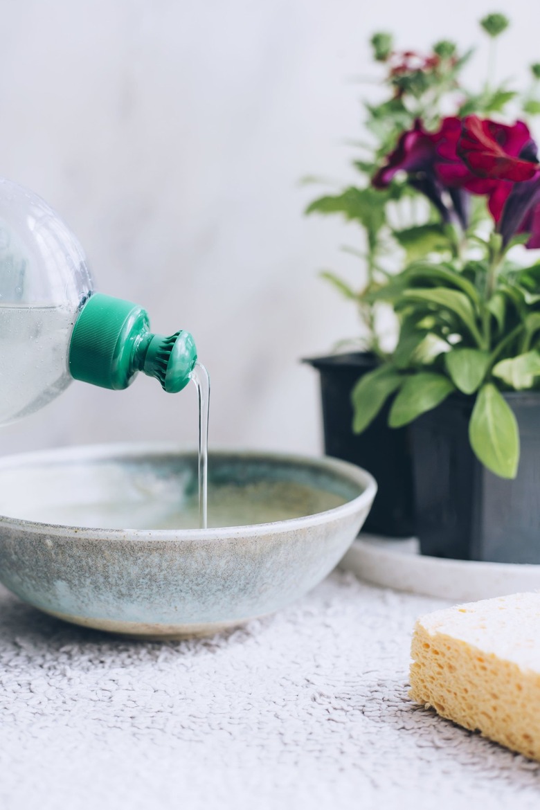 mixing water and dish soap in a ceramic bowl