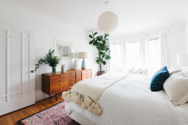 Bedroom featuring midcentury credenza and pom-pom throw blanket