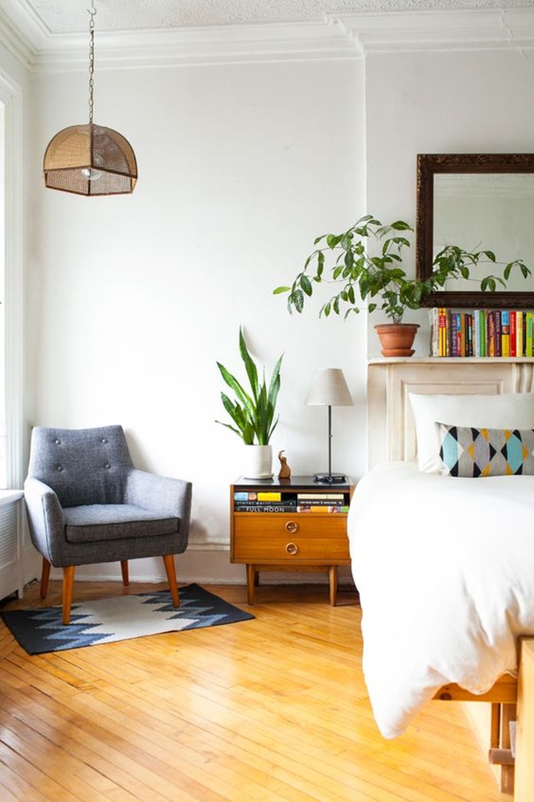 Corner of bedroom with midcentury chair over small area rug