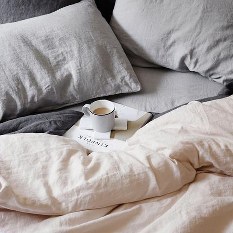 Blush and gray linens on a bed.