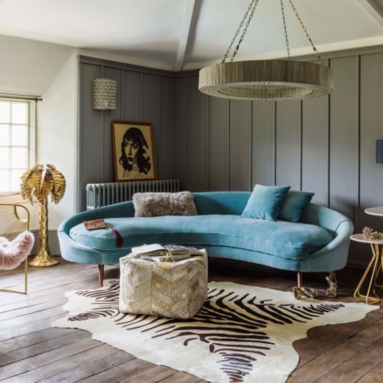 Retro room with turqouse velvet rounded sofa and zebra rug