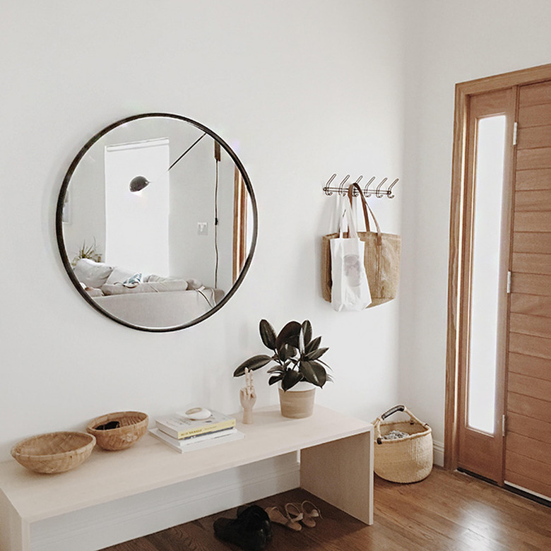 Minimal entryway featuring big round mirror