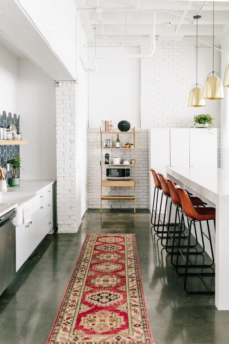 An open kitchen with white-brick walls and a concrete floor.