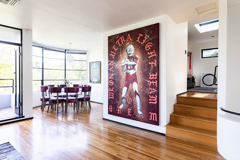 Living room and dining room with wood floors, large paned windows and contemporary art