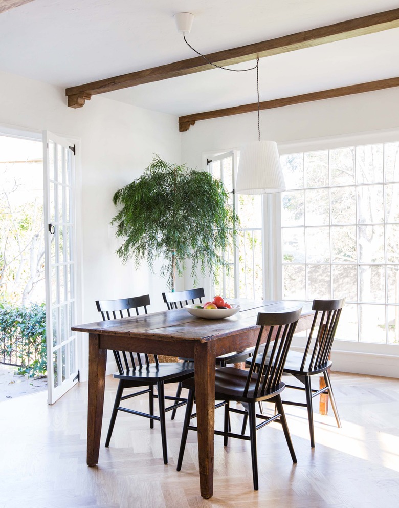 Dark wood table in airy dining room with ceiling beams