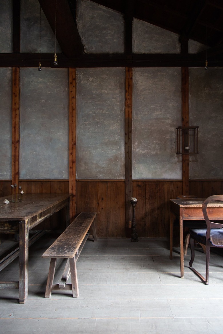 Wooden benches, tables and chairs against concrete walls with wood paneling in low lighting