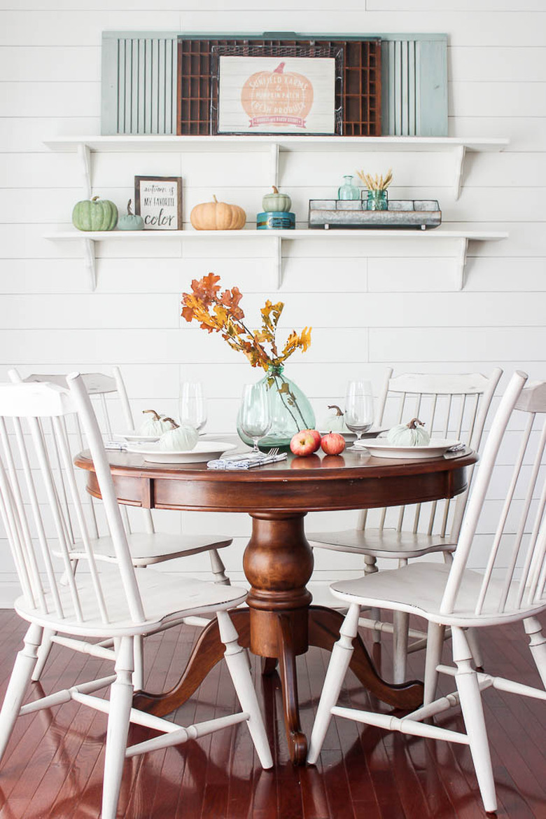 small rustic dining room with round wood table and white chairs