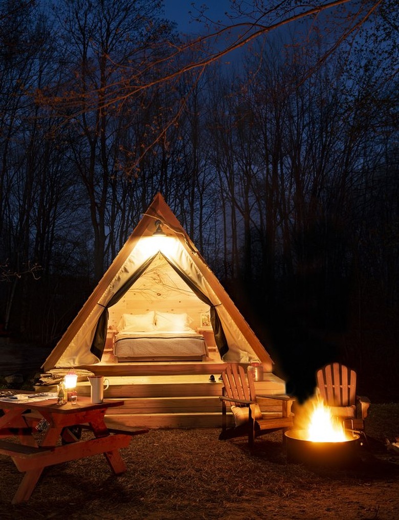 nighttime glamp setup with bonfire and wooden lounge chairs