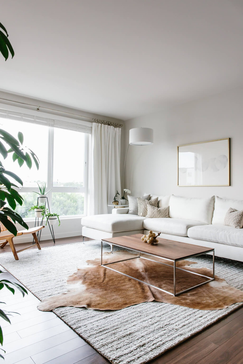 All white living room with layered rugs and large windows.