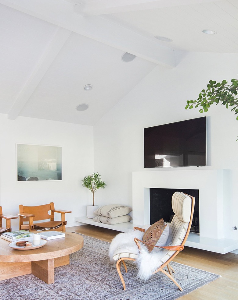 White walled living space with white fireplace and green plants.