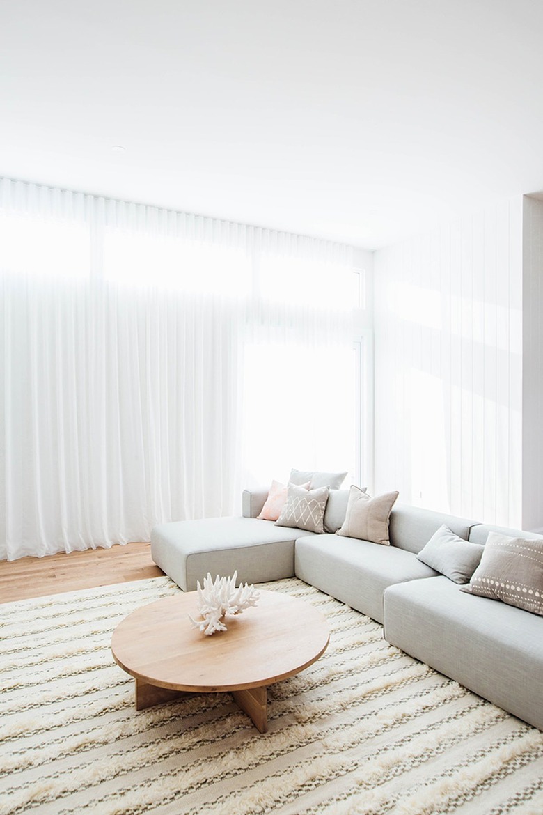 Bright and airy living room with sheer floor to ceiling curtains and a gray couch.