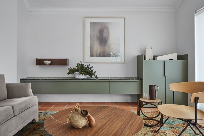 minimalist living room with green cabinets and terra cotta flooring