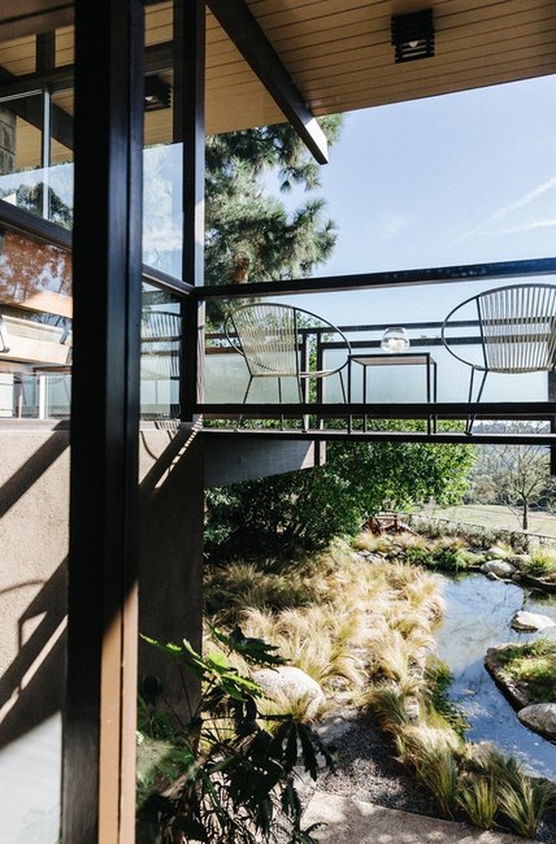 midcentury home with bridge-style balcony overlooking city and backyard stream