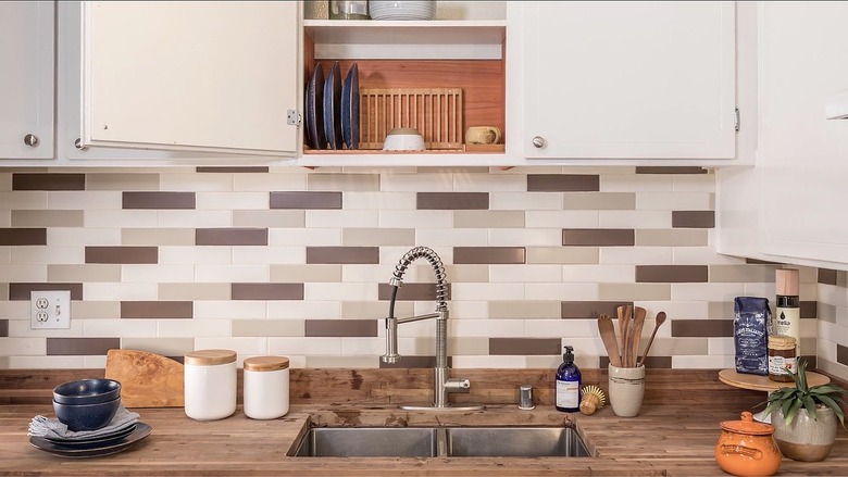 Kitchen with white-gray tile backsplash and wood countertop with white cabinets