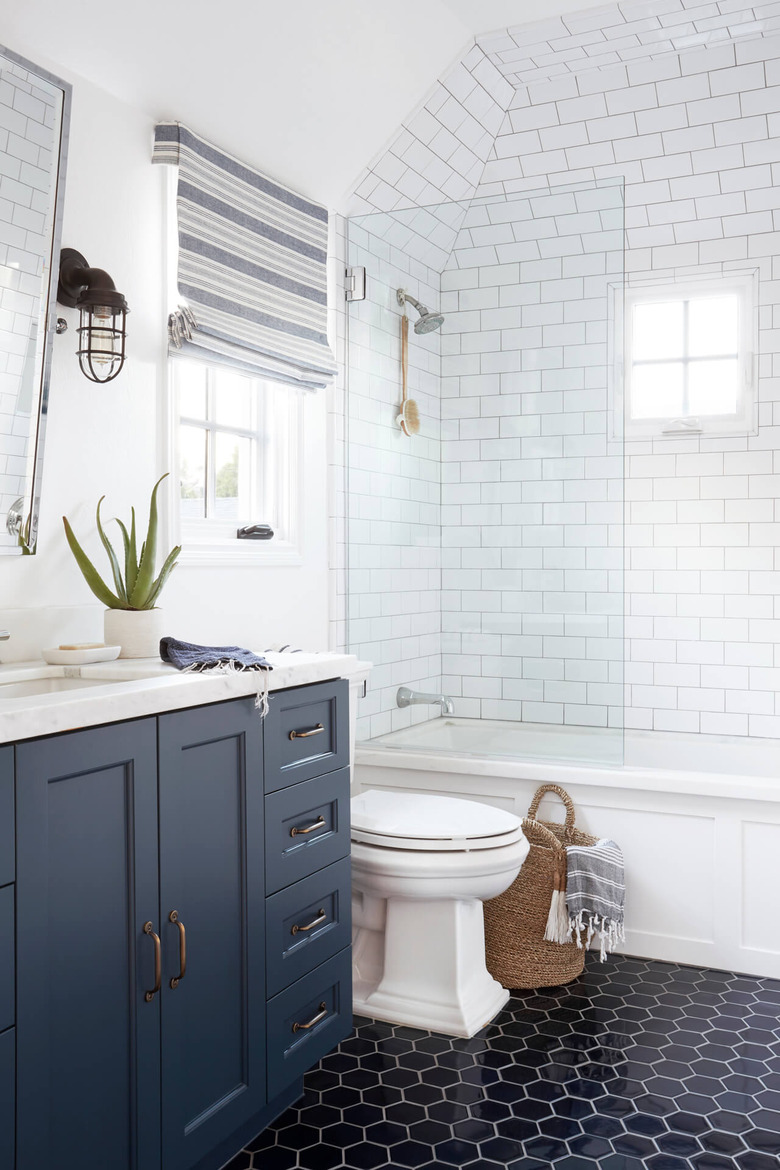 dark bathroom floor tile idea with blue vanity cabinet and subway tile walls in shower