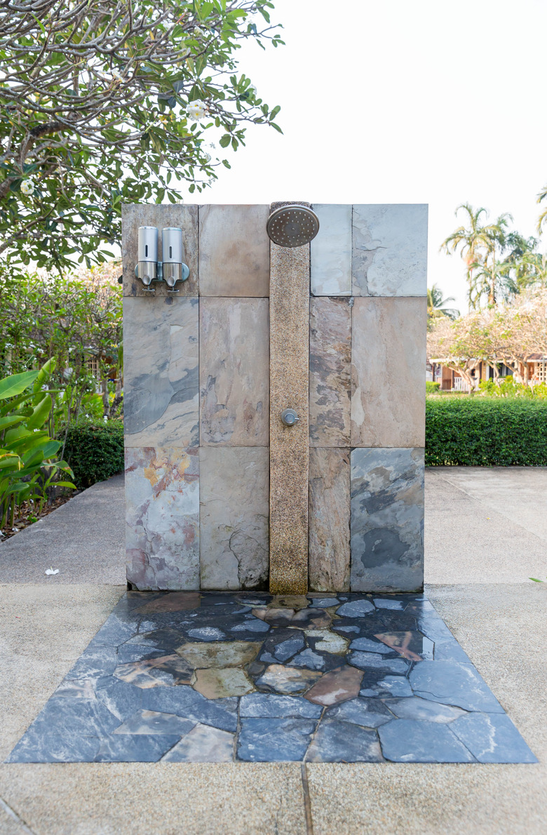 Outdoor shower at swimming pool.  shower cabins behind outdoor swim pool .Outdoor shower area design at the beach, seaside or swimming pool. For person to take a bath and clean up from sea water.