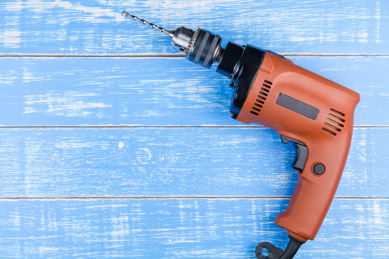 Electric drill with a drill on blue wooden table background