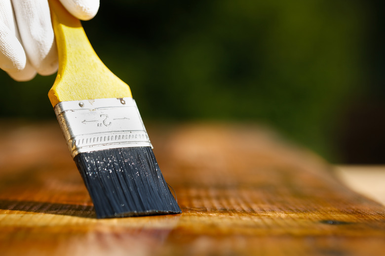 Paintbrush sliding over wooden surface.