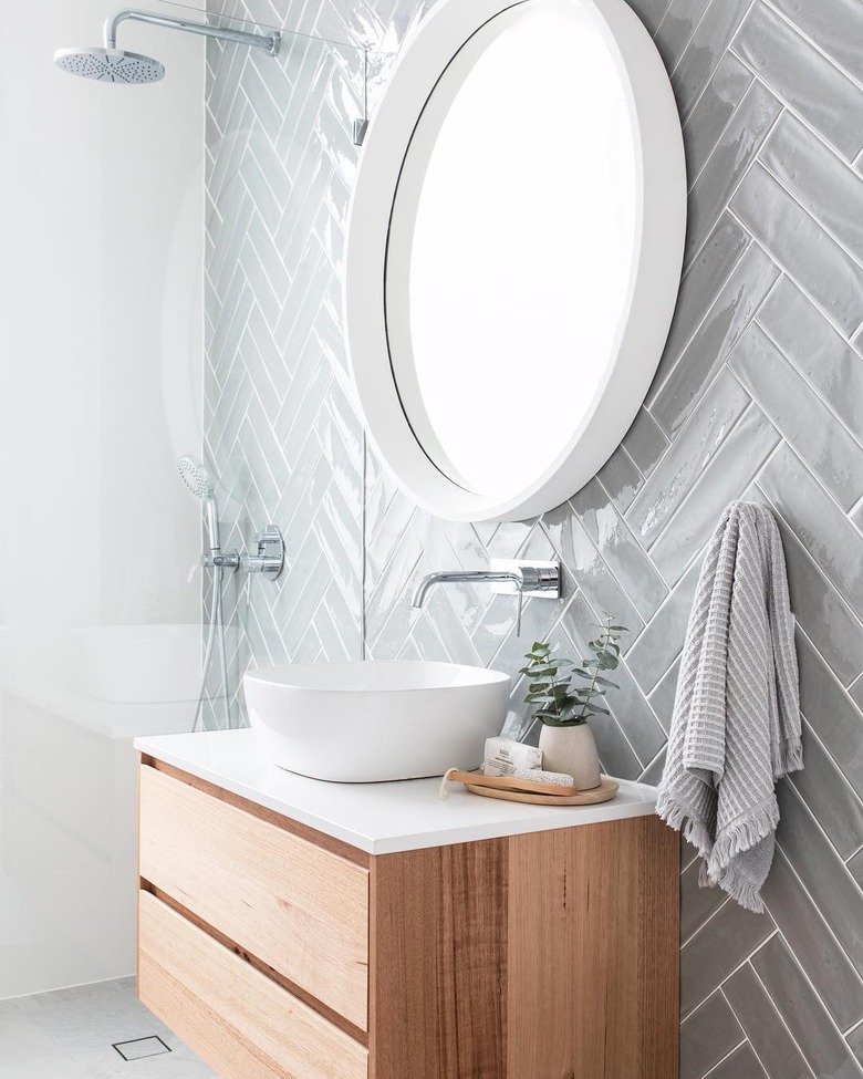 vessel bathroom sink with herringbone tile backsplash and round mirror