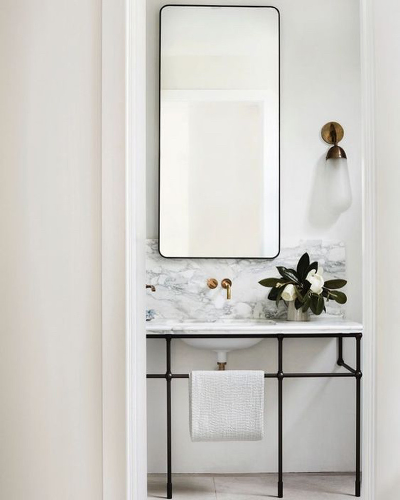 console bathroom sink with marble countertop and backsplash and black metal legs