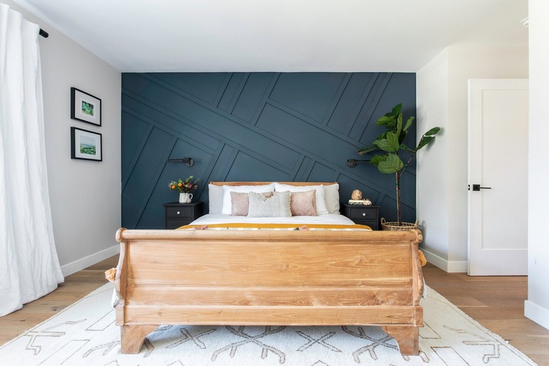 Bedroom with dark teal accent wall and wood bed