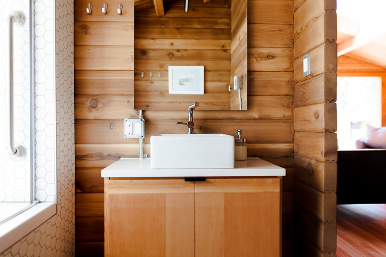 bathroom sink and vanity cabinets on wood wall background with electrical outlet