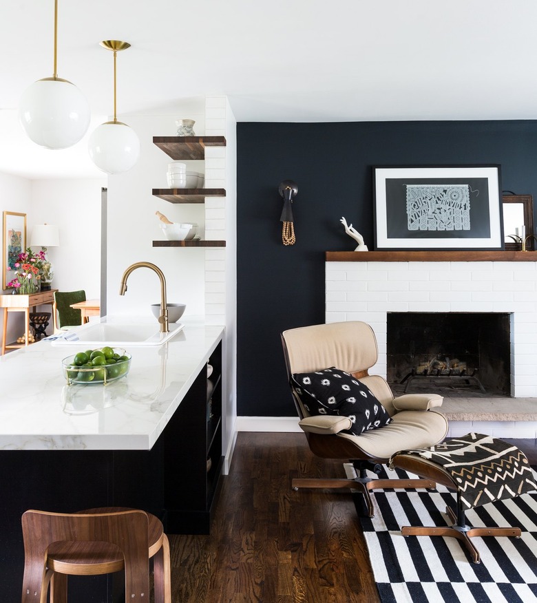 Living room with black accent wall, white fireplace and graphic line rug.