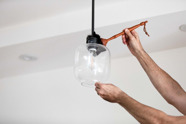 Cleaning glass light pendant with feather duster