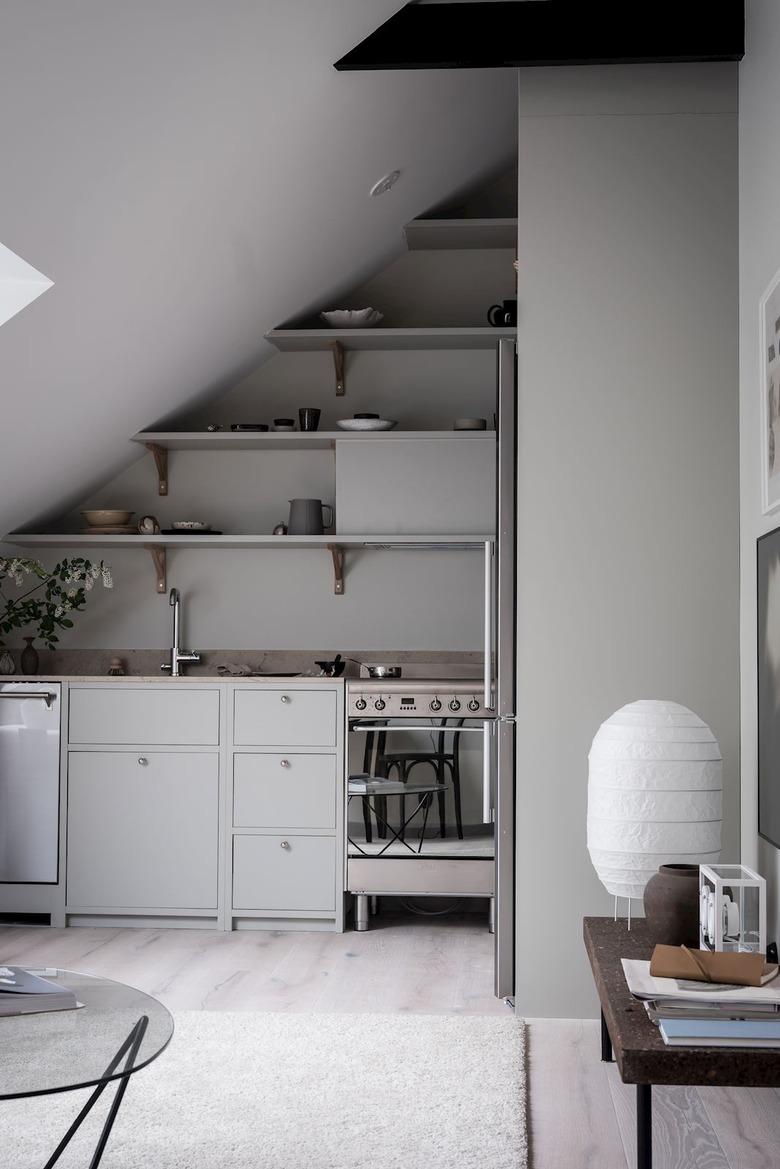 Minimalist kitchen with gray kitchen with apartment size stove and gray open shelves.