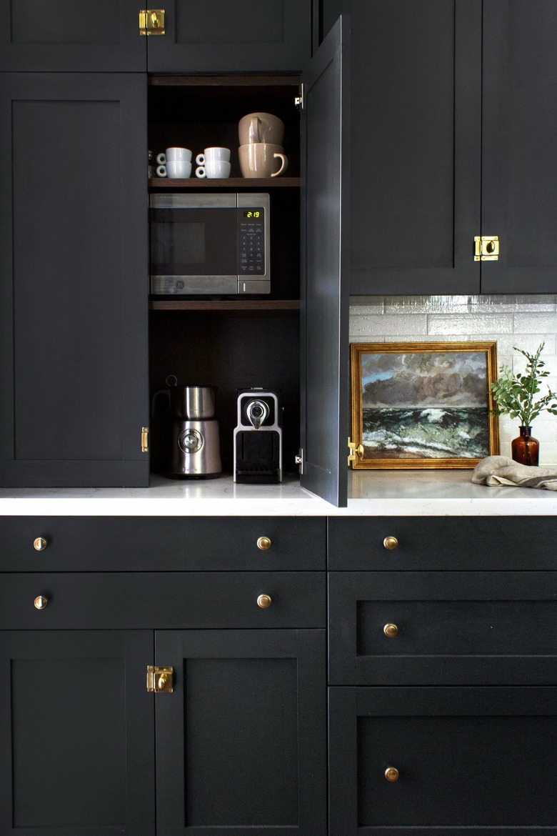 modern black kitchen with appliance garage housing espresso machine, milk frother, toaster, small microwave and blender.