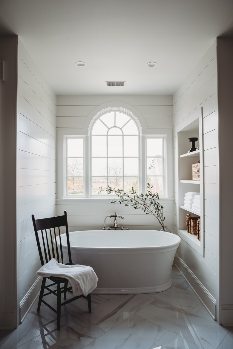 white bathroom with tub and arched window