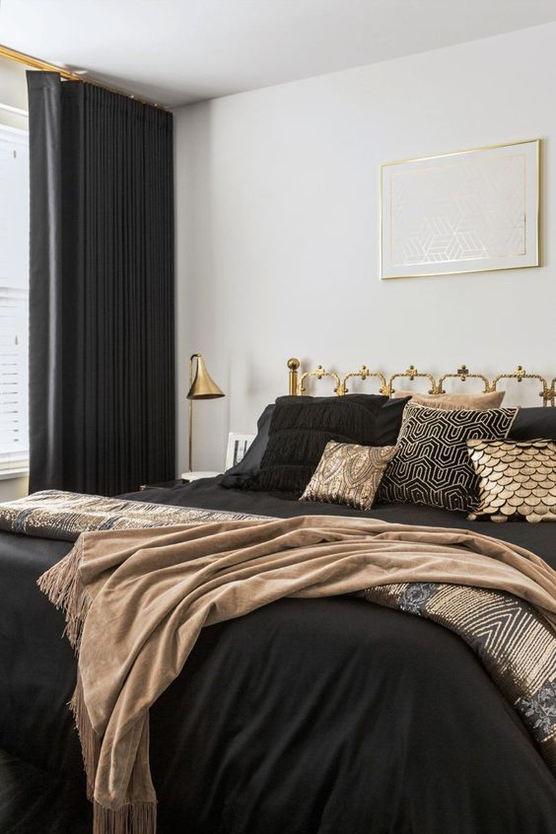 art deco bedroom with shimmering throw pillows on bed and brass fixtures