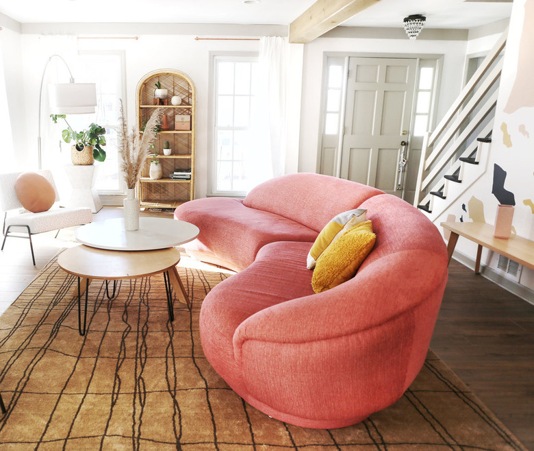 art deco living room with pink curved sofa and rattan bookshelves