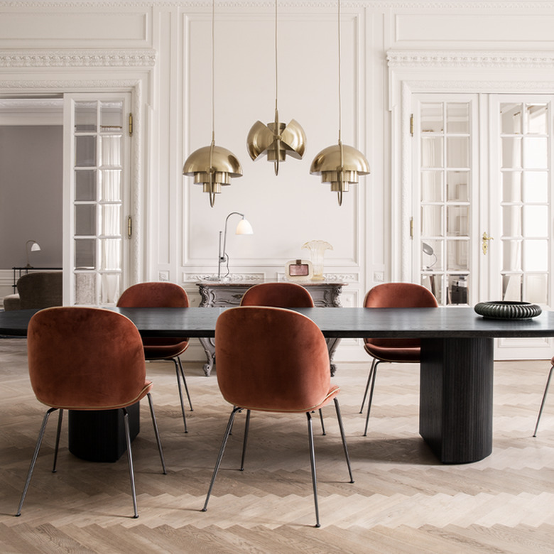 art deco dining room with brass pendants hanging above dining table