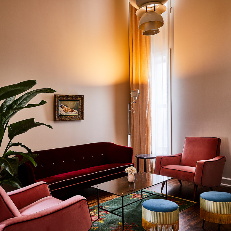 art deco living room with red velvet sofa, pink velvet armchairs, sleek coffee table and fringed footstools