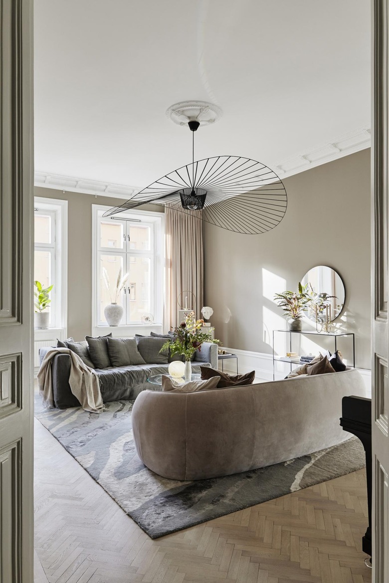 Gray and beige art deco living room with dramatic, black fan frame pendant light and cream colored sofas