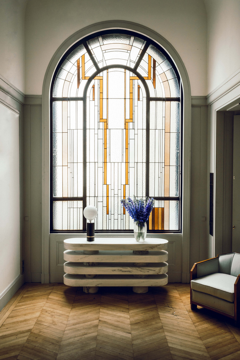 arched art deco stained glass window in front of modern console table