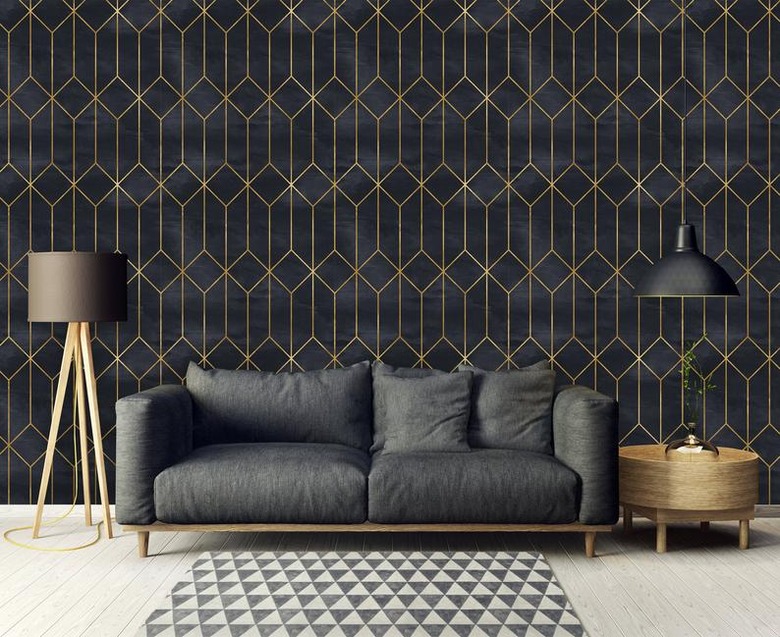 living room space with black couch and black and gold geometric wallpaper in the background