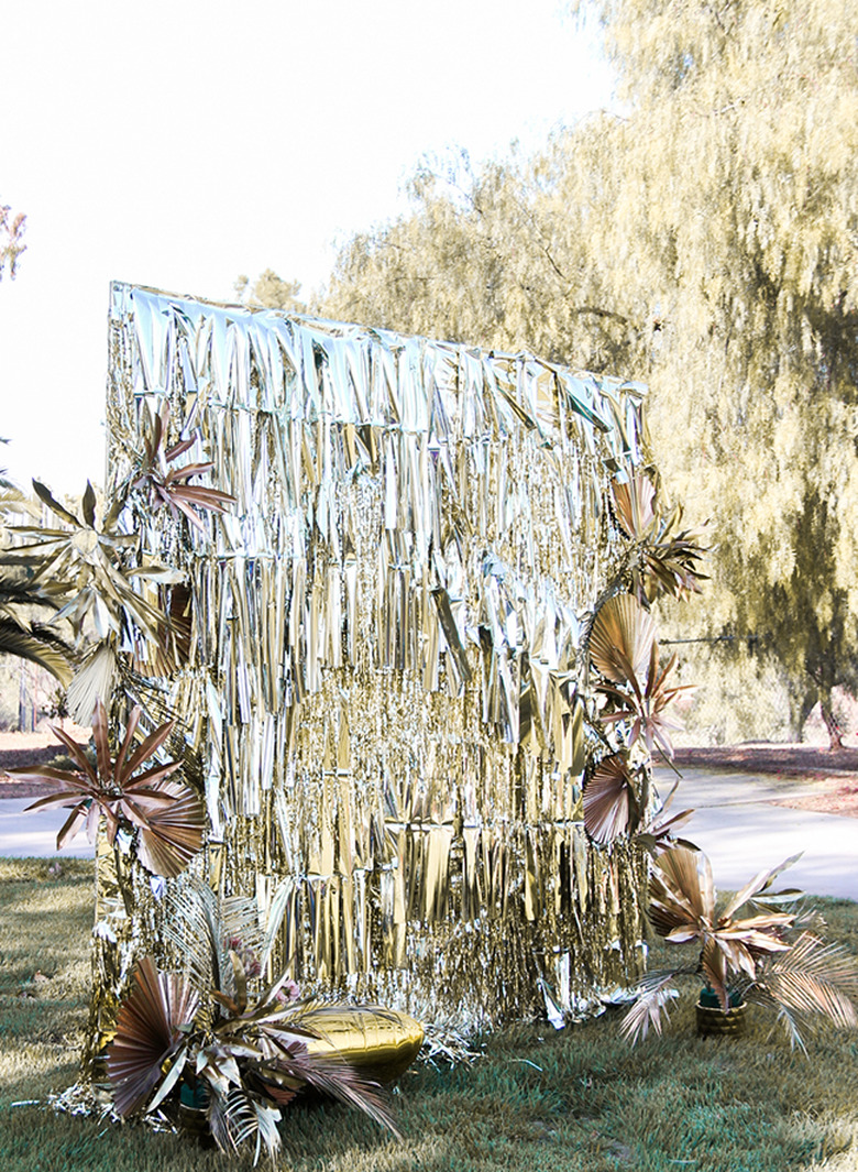 art deco themed party idea with gold fringe photo booth backdrop outside