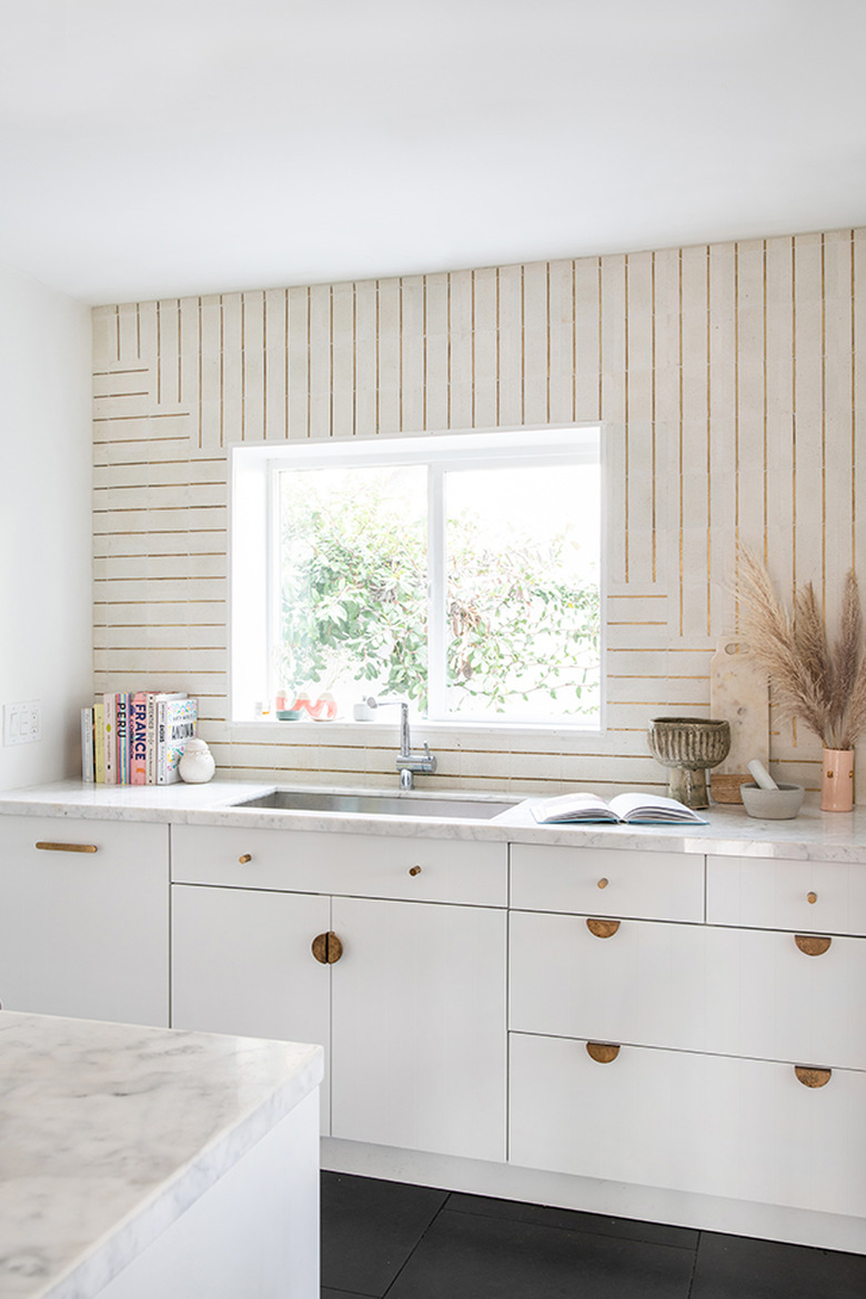 Art deco tile backsplash with brass inlaid details in modern white kitchen