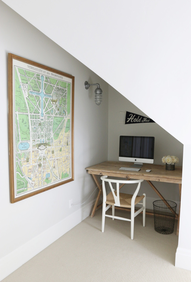 attic apartment nook with small wood desk, wood chair, computer, map on wall.